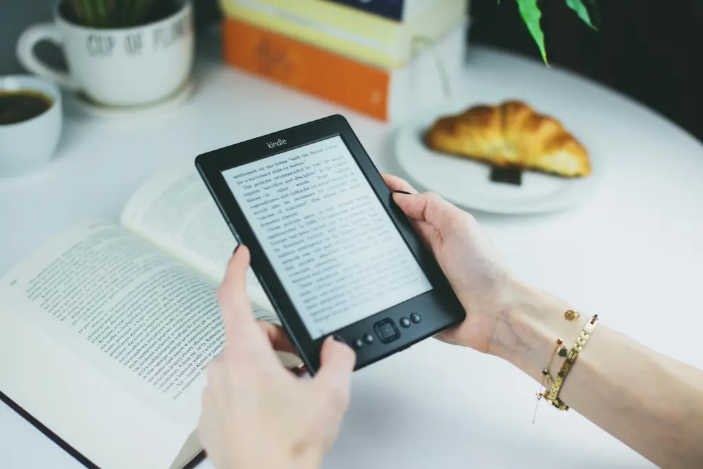 A woman holding an Amazon Kindle in both hands.